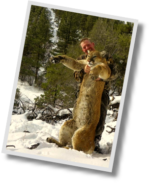 Photo of smiling hunter holding up dead lion in snowy forest.