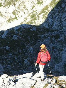 Lone hiker in red parka traverses a mountain pass.
