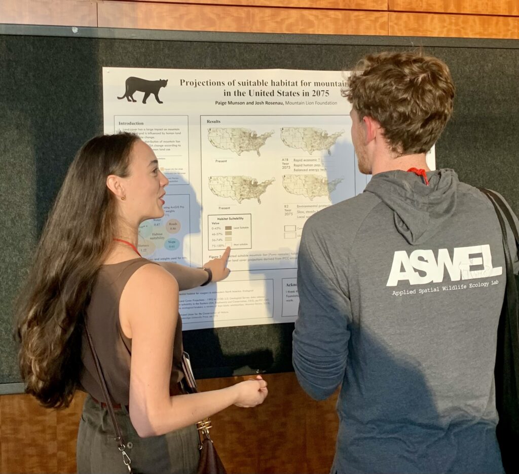 Paige Munson shows her poster to a conference attendee